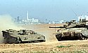 Nahal Oz - Israeli tanks patrol the border with the Gaza Strip whose houses are seen in the background.  Photo: Eliyaju Ben Yigal/Jinipix/Israel Sun