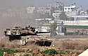 Nahal Oz - Israeli tanks patrol the border with the Gaza Strip whose houses are seen in the background.  Photo: Eliyaju Ben Yigal/Jinipix/Israel Sun